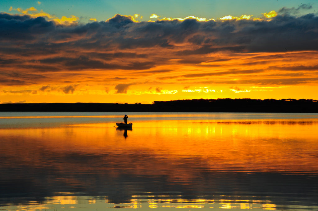 Man fishing on the lake at sunset